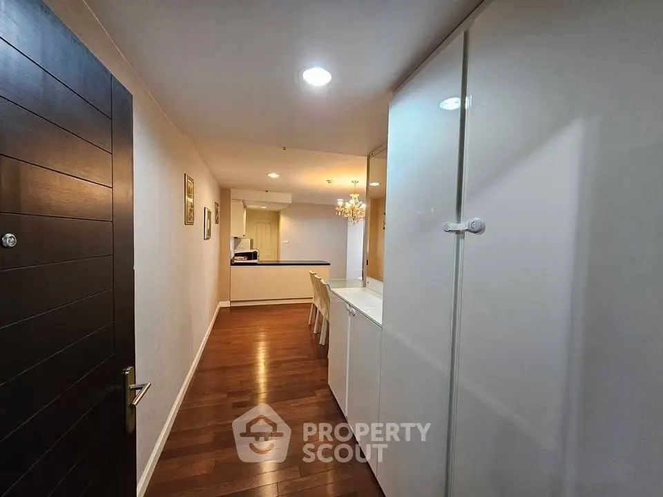Spacious hallway with wooden flooring leading to a modern kitchen and dining area.