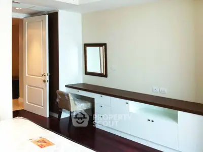 Elegant bedroom with modern furniture and hardwood floors, featuring a stylish desk and mirror.