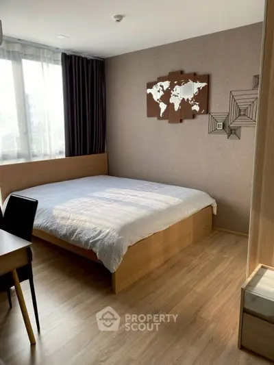 Modern bedroom with wooden flooring and stylish wall art, featuring a cozy bed and natural light.
