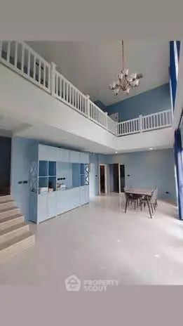 Spacious modern living room with high ceilings and elegant chandelier in a duplex apartment.