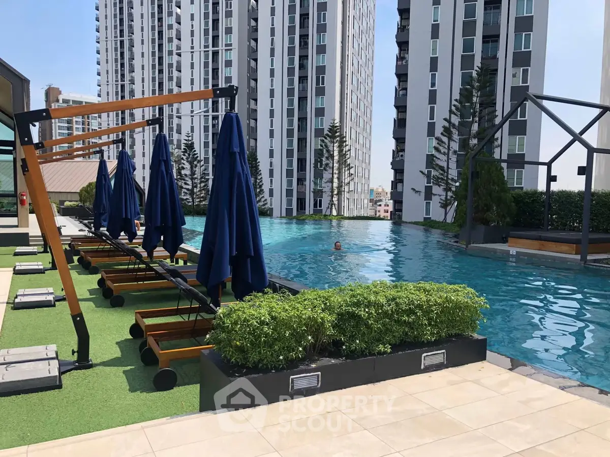 Luxurious rooftop pool with modern high-rise buildings and sun loungers, perfect for urban living.