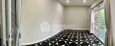 Spacious room with elegant black and white tiled flooring and large windows for natural light.