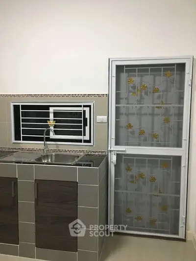 Modern kitchen with sleek cabinetry and secure metal door, ideal for urban living.