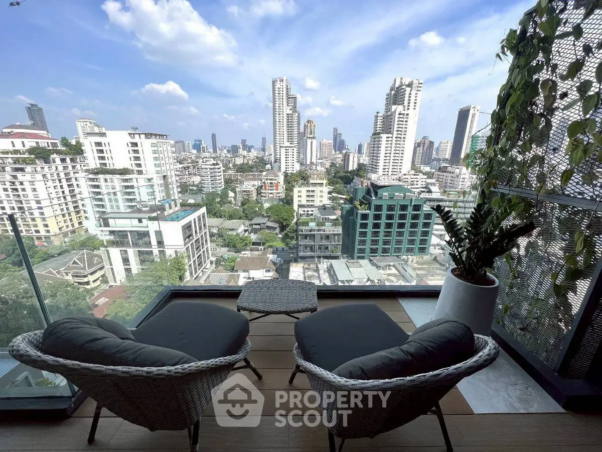 Stunning cityscape view from a modern balcony with cozy seating area, perfect for relaxation.