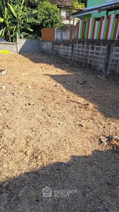 Vacant land plot with potential for development, surrounded by residential buildings and greenery.