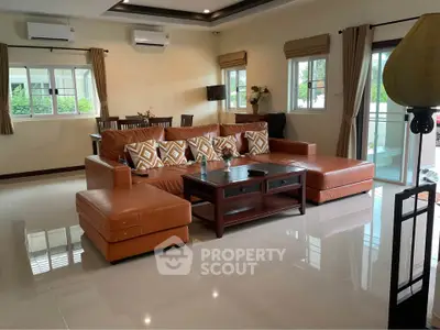 Spacious living room with modern leather sofa and large windows for natural light.