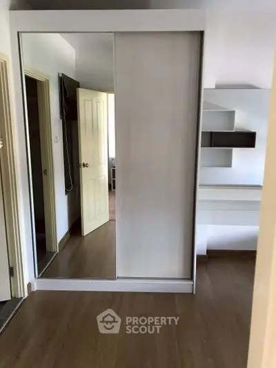Spacious bedroom with mirrored wardrobe and wooden flooring