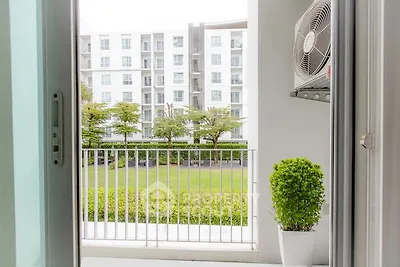 Modern apartment balcony with lush garden view and air conditioning unit.