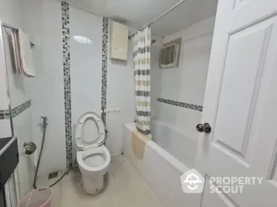 Modern bathroom with a clean white design, accented by stylish mosaic tiles, featuring a full bathtub, toilet, and a window for natural light.