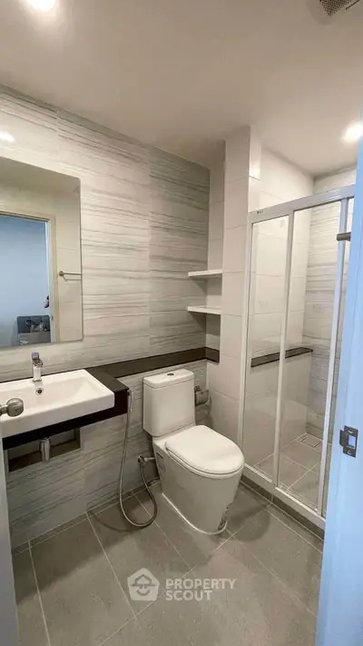 Modern bathroom with sleek design, featuring a glass shower enclosure and contemporary fixtures.