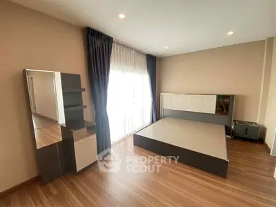 Spacious bedroom with modern furnishings and large window for natural light.