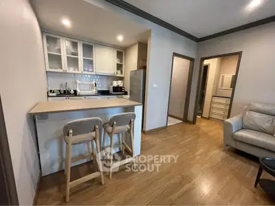 Modern open-layout kitchen with breakfast bar and cozy living area in stylish apartment.