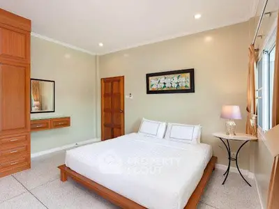Spacious bedroom with elegant decor and natural light, featuring a comfortable bed and stylish wooden furniture.