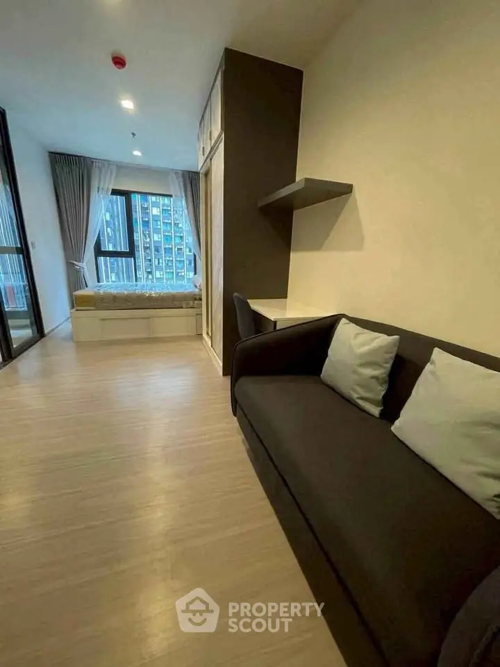 Modern studio apartment with cozy living area and large window view.