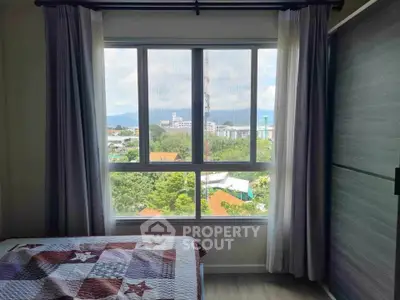 Cozy bedroom with large window offering scenic city and mountain views.