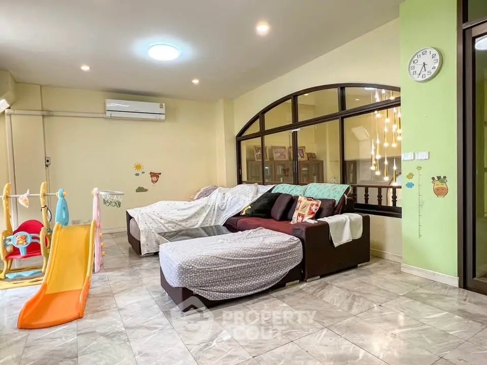 Spacious living room with cozy seating and playful children's slide, perfect for family gatherings.