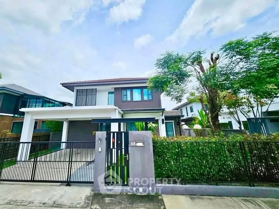 Modern two-story house with gated driveway and lush greenery