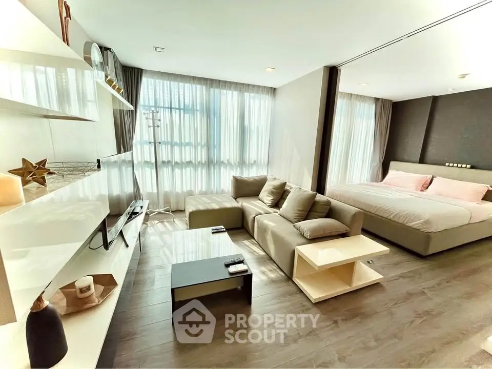 Modern open-plan living room and bedroom with stylish decor and natural light