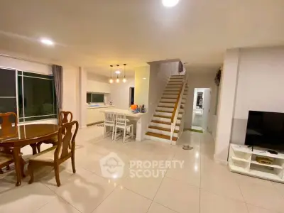 Spacious open-plan living and dining area with modern kitchen and elegant staircase.