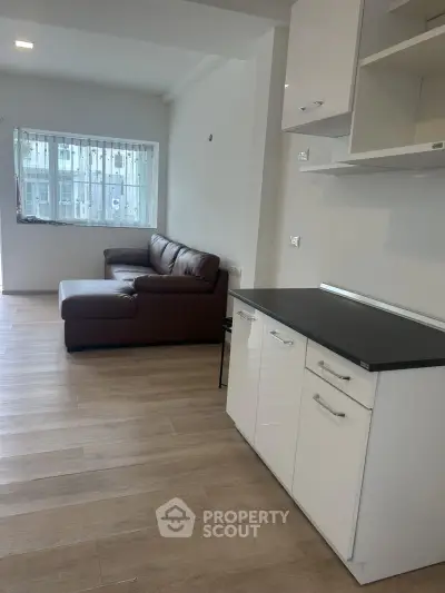 Modern living room with sleek kitchen and cozy sofa, perfect for urban living.