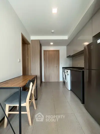 Modern kitchen with sleek appliances and compact dining area in a stylish apartment.