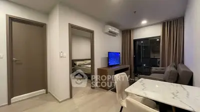 Modern living room with open layout, featuring a cozy sofa, TV, and dining area, leading to a bedroom.