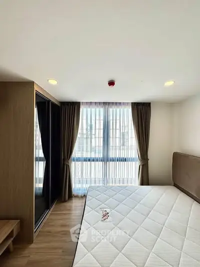 Modern bedroom with large window and stylish furnishings in a contemporary apartment.