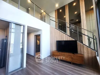 Modern duplex living room with stylish wooden accents and sleek glass railing staircase.