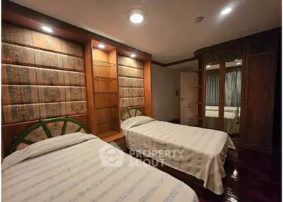 Cozy bedroom with twin beds and elegant wooden wardrobe, perfect for a comfortable stay.