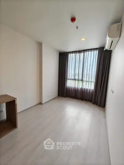 Spacious empty room with large window and air conditioning, perfect for customization.