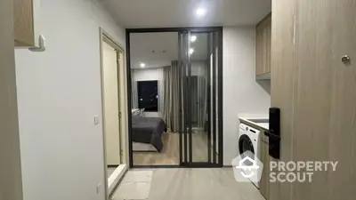 Modern apartment entrance with washing machine and view into bedroom