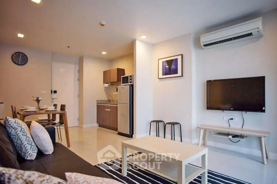Modern living room with open kitchen, stylish decor, and air conditioning in a cozy apartment.