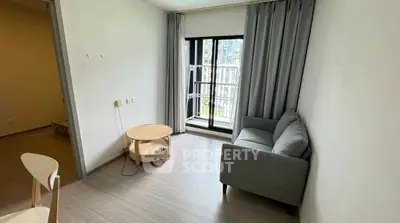 Cozy living room with modern gray sofa and small round table near window.