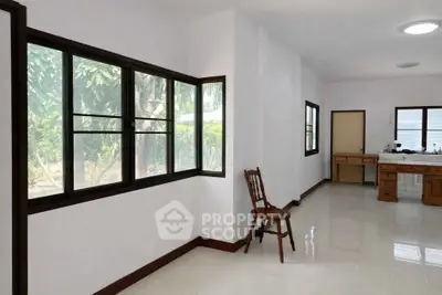 Spacious interior with large windows and natural light, featuring a simple chair and desk setup.