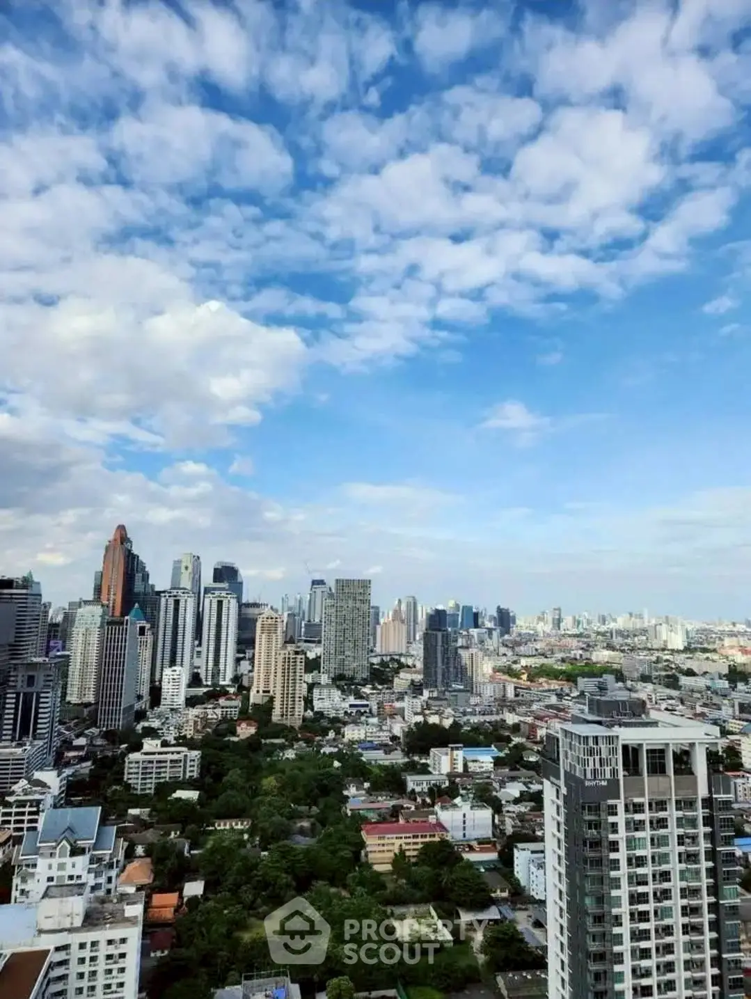 Stunning cityscape view from a high-rise building showcasing urban skyline and blue skies.