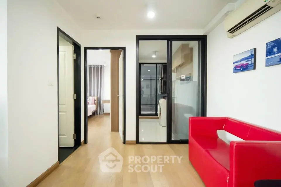 Modern apartment interior with red sofa and wooden flooring, showcasing a bright and inviting living space.
