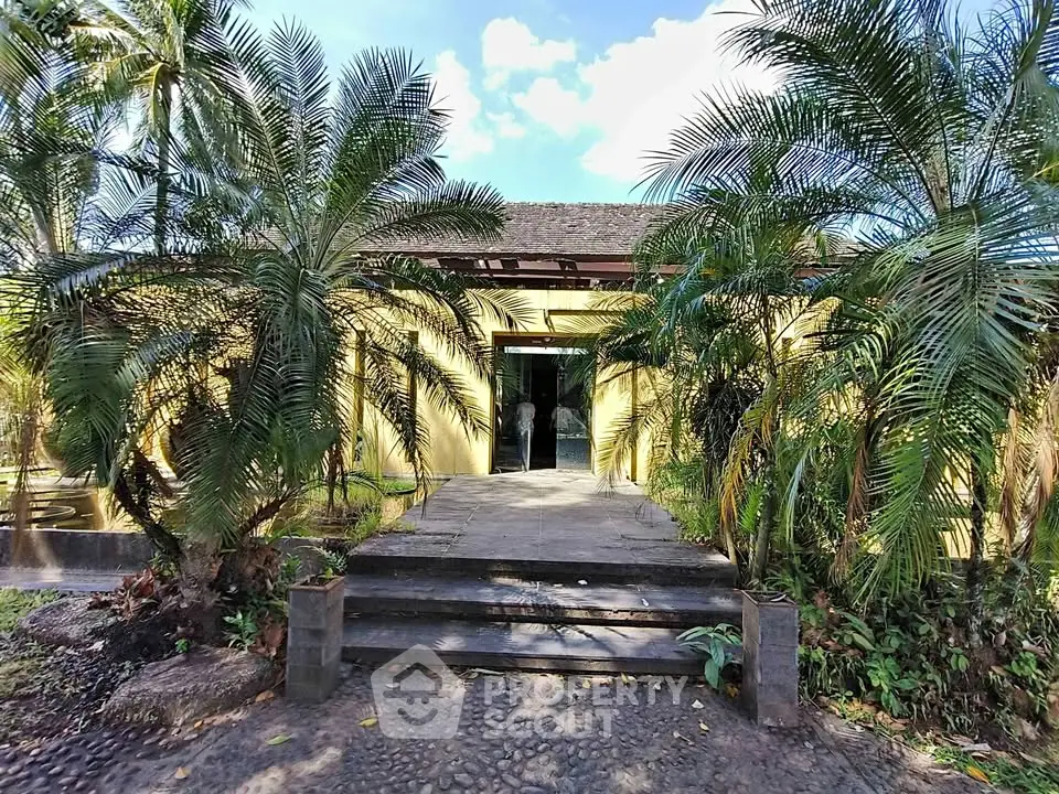 Tropical villa entrance surrounded by lush greenery and palm trees