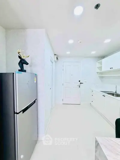 Modern kitchen with sleek white cabinets and stainless steel fridge in bright apartment