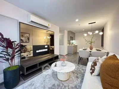 Modern living room with stylish decor and open dining area, featuring elegant lighting and cozy ambiance.