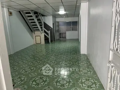 Spacious interior with green patterned flooring and staircase, ideal for customization.