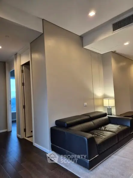 Modern living room with sleek black leather sofa and elegant lighting, showcasing contemporary interior design.