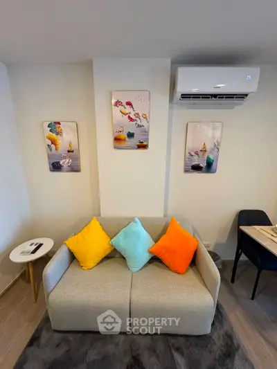 Modern living room with colorful cushions and wall art, featuring a cozy sofa and air conditioning unit.