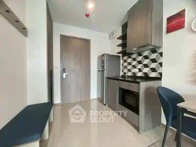 Modern compact kitchen with sleek cabinetry and geometric backsplash in a stylish apartment.