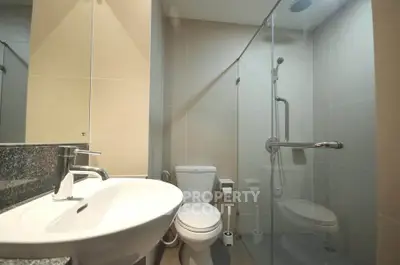 Modern bathroom with glass shower and sleek fixtures in contemporary apartment.