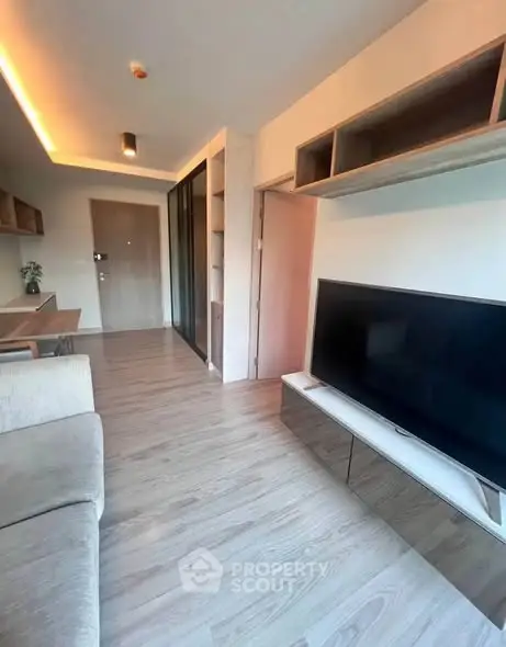 Modern living room with sleek TV setup and stylish wooden flooring.