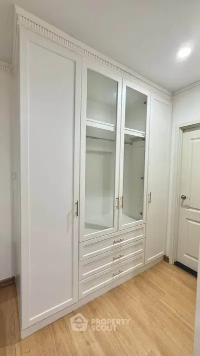 Elegant white wardrobe with glass doors in a modern interior space