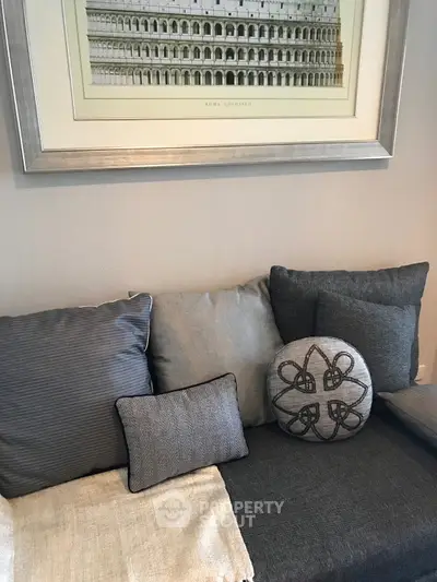 Cozy living room corner with stylish cushions and framed artwork, perfect for relaxation.