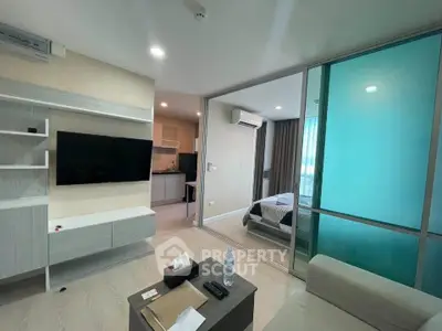 Modern living room with open layout and view into bedroom, featuring sleek furniture and contemporary design.