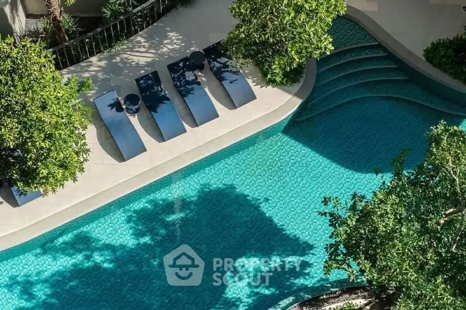 Luxurious outdoor pool area with sun loungers and lush greenery, perfect for relaxation and leisure.