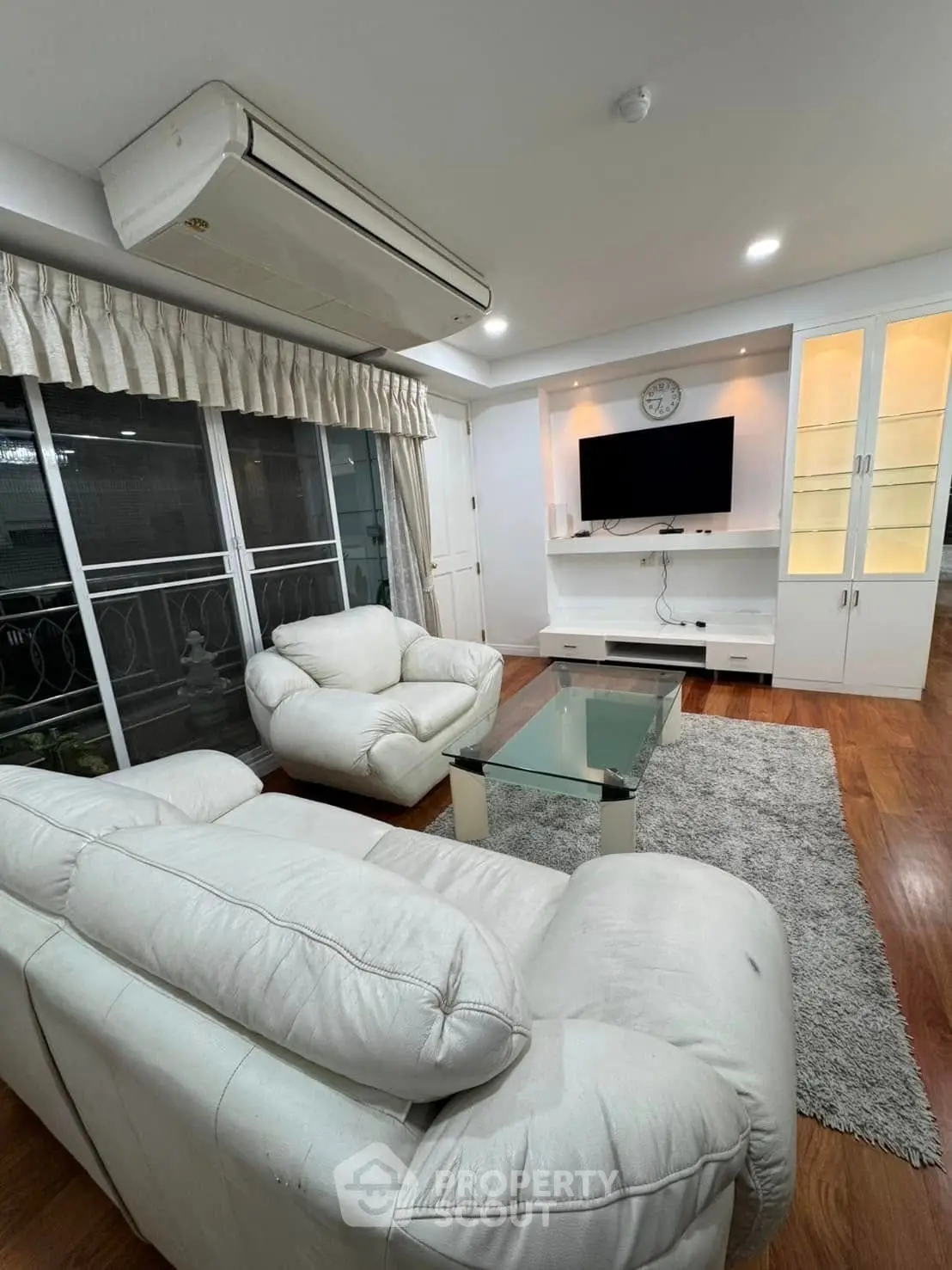 Spacious living room with plush white sofas and modern entertainment center